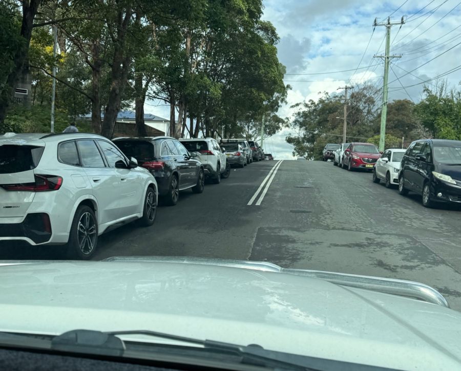 Parked cars force drivers to illegally straddle double white lines on the approach to a blind crest.